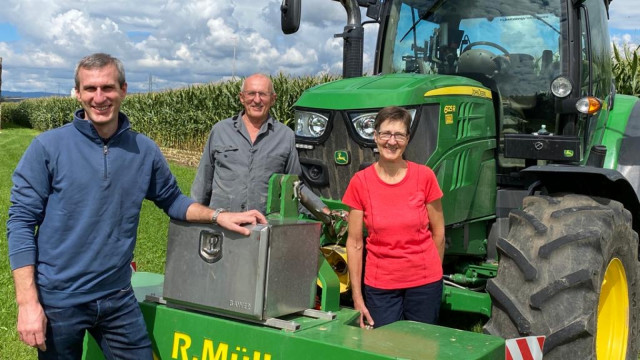 Raphael Müller posiert mit seinen Eltern Christian und Vreny vor dem Traktor